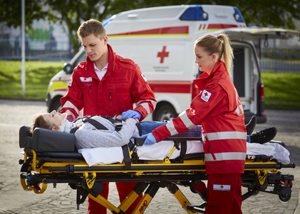 Ein Zivildiener und eine Mitarbeiterin im freiwilligen Sozialjahr betreuen eine Patientin auf der Trage.