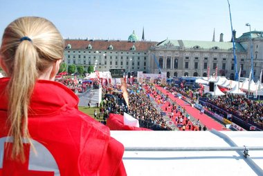 Vienna City Marathon: Eine Rotkreuz-Mitarbeiterin blickt auf die Menschenmasse beim Zieleinlauf des Marathons. Sie sorgt für Sicherheit.