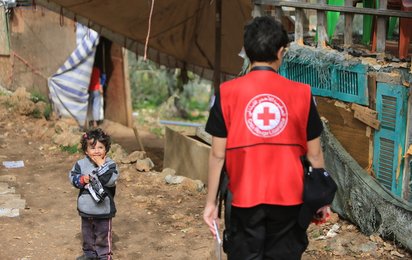 Rotkreuz Helferin mit Kleinkind im Flüchtlingslager