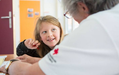 Lesepaten Wolkersdorf, eine Rotkreuz-Mitarbeiterin unterstützt ein Schulkind beim Lernen.