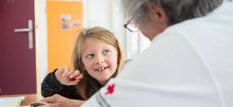 Lesepaten Wolkersdorf, eine Rotkreuz-Mitarbeiterin unterstützt ein Schulkind beim Lernen.