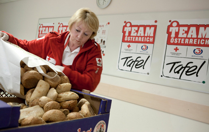 Auf dem Bild eine Dame die eine große Menge Brot in von einem Sackerl in eine Kiste leert