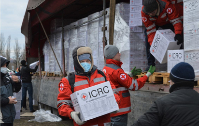 Ein Mitarbeiter des Ukrainischen Roten Kreuzes trägt ein Hilfspaket mit dem Schriftzug "ICRC"