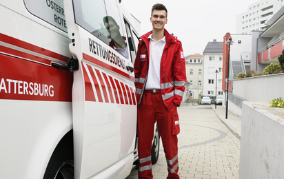 Zivildiener unterstützen das Rote Kreuz: so auch Manuel, der gerade in Uniform bereit zum Dienst neben dem Rettungswagen steht.