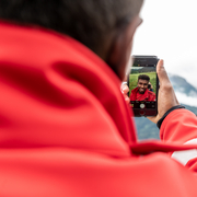 Anas ist geflüchtet und wohnt nun in Tirol. Er trägt schon mit Stolz eine rotes Rotkreuz Jacke und schaut sich dabei selbst in seinem Handy an. Anas ist get social Jugendreporter des Roten Kreuzes