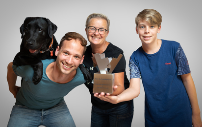 3 Menschen und ein Hund halten die Trophäe von Henri.DerFreiwilligenpreis in die Kamera.