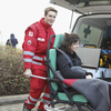 Krankentransport-Team des Roten Kreuzes hebt eine Patientin aus dem Rettungswagen