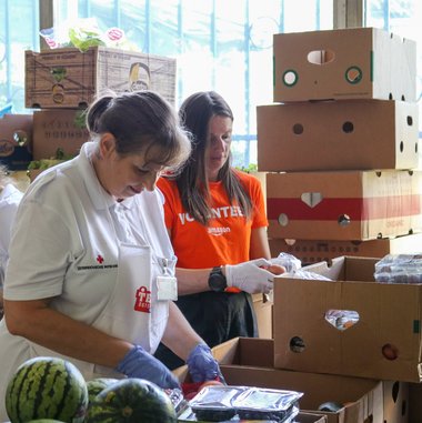 Zwei Frauen, eine von der Team Österreich Tafel und eine von Amazon, sortieren zusammen Lebensmittelspenden.