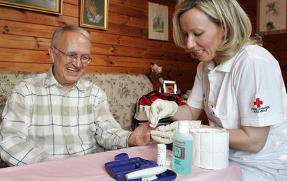 Krankenschwester misst im Rahmen der mobilen Pflege den Blutzucker eines Patienten.