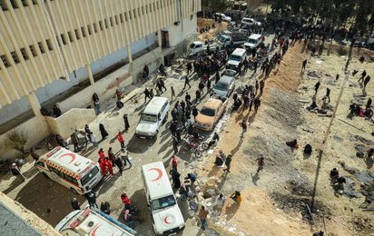 Von oben aufgenommene chaotische Szenen vor Sednaya in Syrien. Mitarbeiter und Autos des Syrisch-Arabischen Roten Halbmond stehen davor.