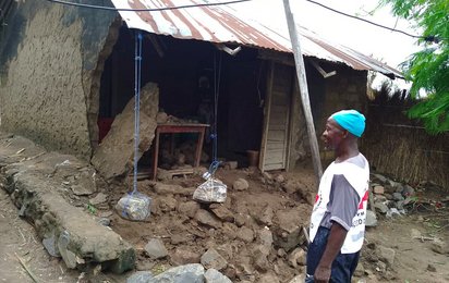 Mitarbeiter des Roten Kreuzes steht vor einem kaputten Haus in Mozambik nach Wirbelsturm Chido