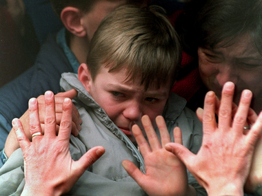 A father's hands press against the window of a bus carrying his tearful son and wife to safety from the besieged city of Sarajevo during the Bosnian War on Nov. 10, 1992.