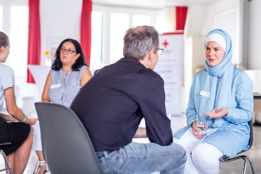 Eine Frau muslimischen Glaubens im Gespräch mit einem Mann. Im Projekt CrossTalk geht es um interkulturellen und interreligiösen Austausch.