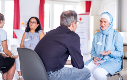 Eine Frau muslimischen Glaubens im Gespräch mit einem Mann. Im Projekt CrossTalk geht es um interkulturellen und interreligiösen Austausch.