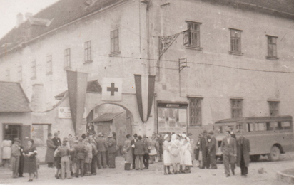 Historisches Rotkreuz-Foto, Haus der Begegnung in Eisenstadt, davor Rotkreuz-Mitarbeiter mit Beflaggung