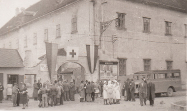 Historisches Rotkreuz-Foto, Haus der Begegnung in Eisenstadt, davor Rotkreuz-Mitarbeiter mit Beflaggung