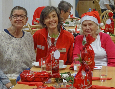 Rotkreuz Mitarbeiterin lächelt mit zwei Besucherinnen des Seniorentreffs in die Kamera