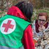 Eine Mitarbeiterin der Krisenintervention spricht mit einer Frau, die in einer Rettungsdecke eingewickelt ist. Sie bekommt psychosoziale Unterstützung während einer Krise