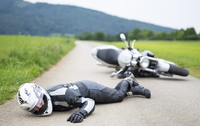 Unfall mit einem Motorrad. Ein Motorradfahrer mit Helm liegt auf dem Boden.