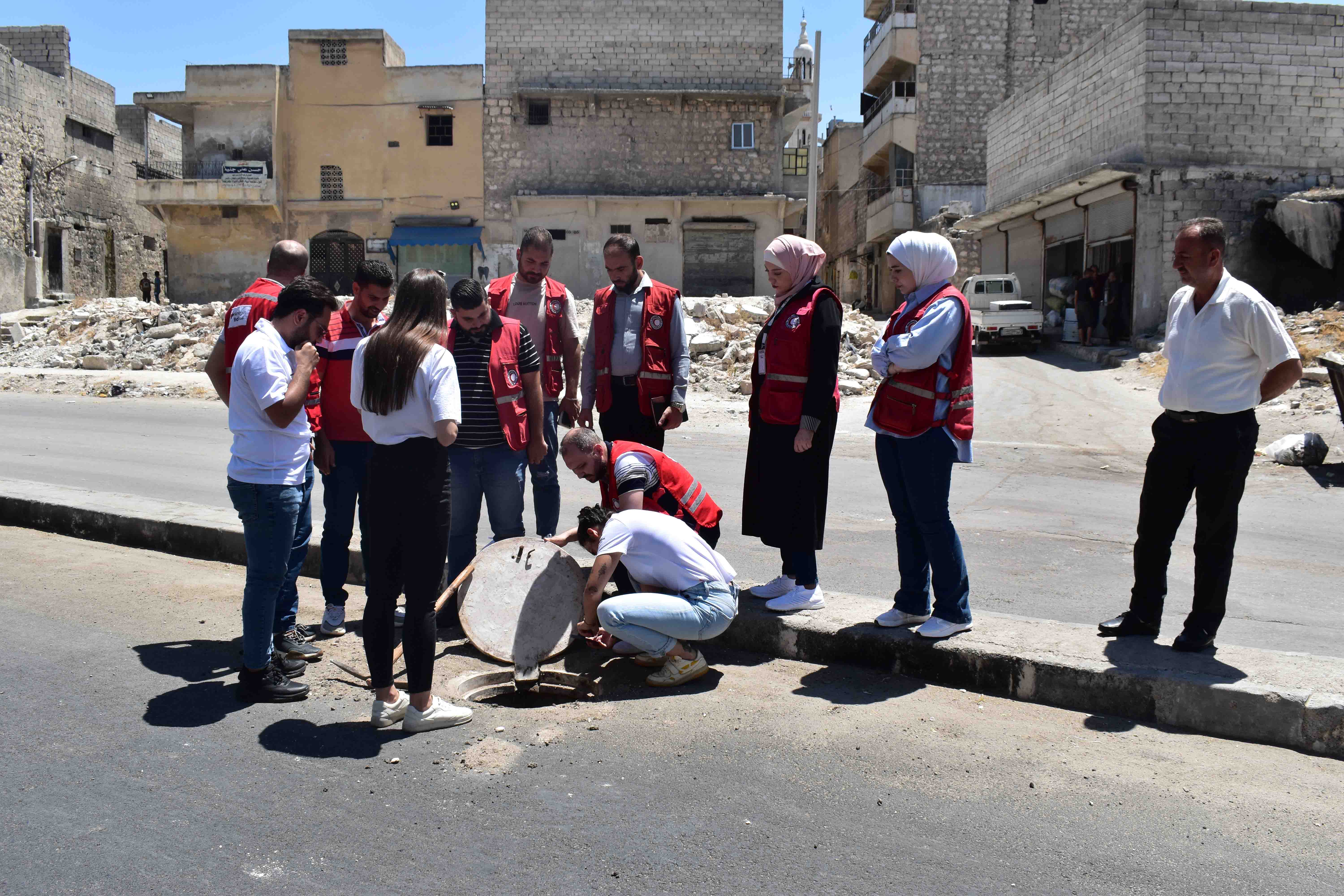 Personen schauen auf Kanaldeckel in Aleppo, Syrien