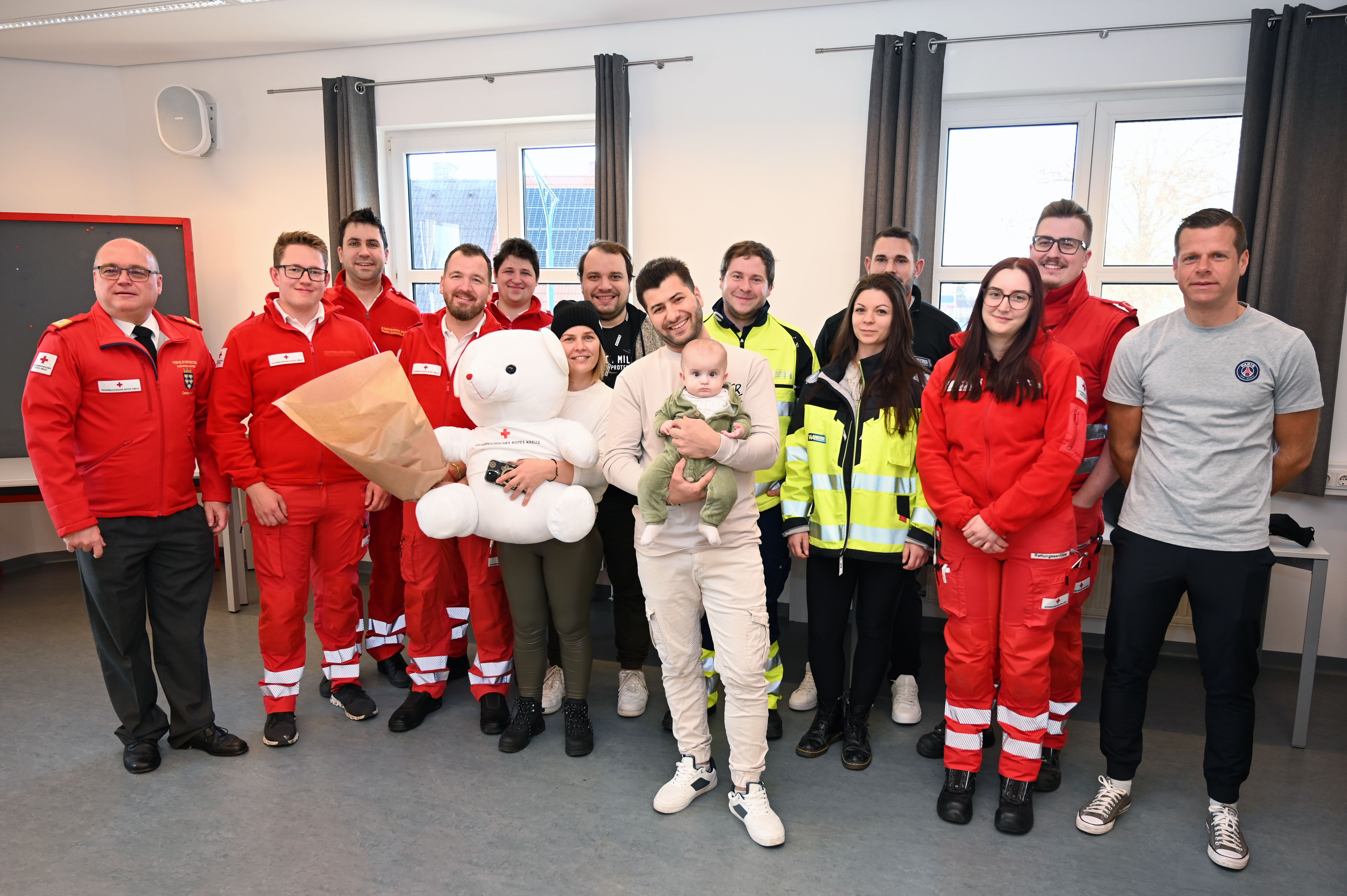 Gruppenfoto der Lebensretter:innen, des Elternpaars und der kleinen Mara