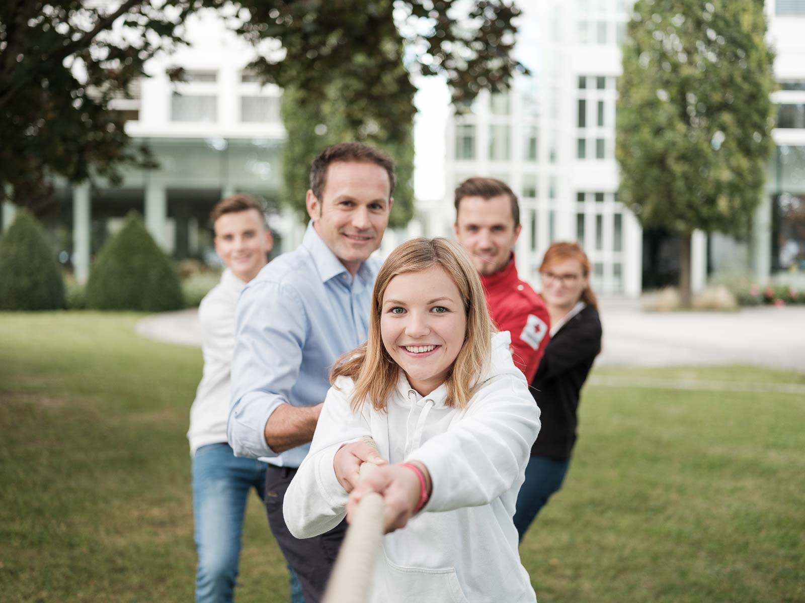 Fünf Menschen ziehen gemeinsam an einem Seil.