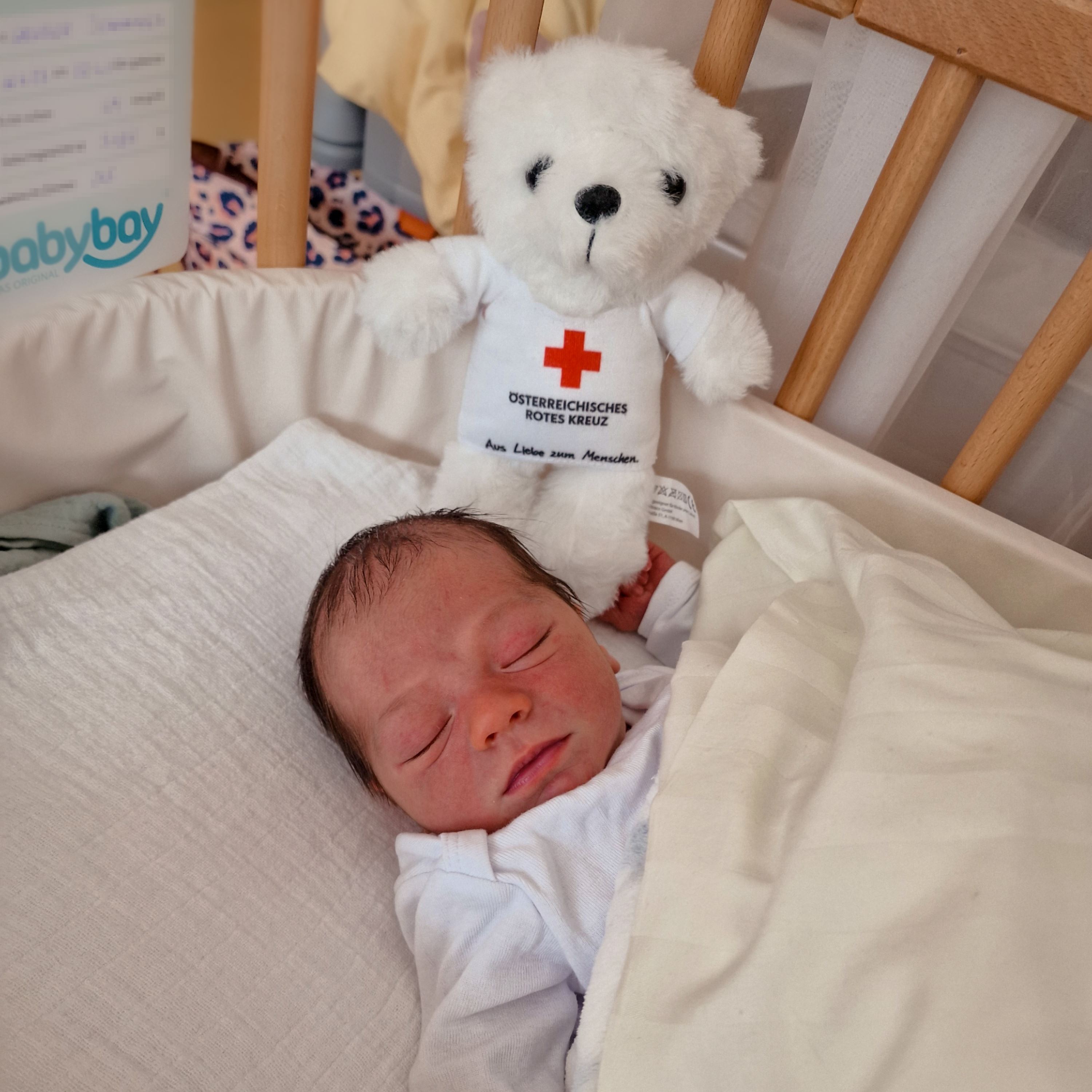 Der kleine Johannes liegt im Babybett des Krankenhauses.